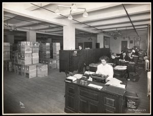 1910年にニューヨークのハドソンウントヴェストリーストリートにあるパークス、デービスウント社、化学者の発送室のように見えるデスクの男性と女性の様子（シルバーゼラチンプリント）